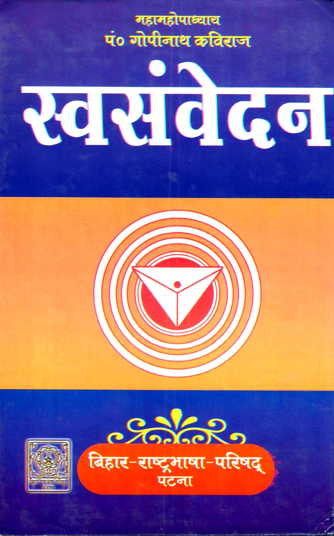 A book cover in Devanagari script, featuring a blue and orange color-blocked design with a central white and red circular emblem.